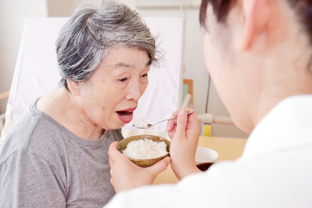 女性にご飯を食べさせる介護士